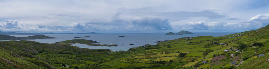 Expansive view of Irelands Atlantic coast, featuring lush green landscapes and scattered islands under a dramatic sky.
