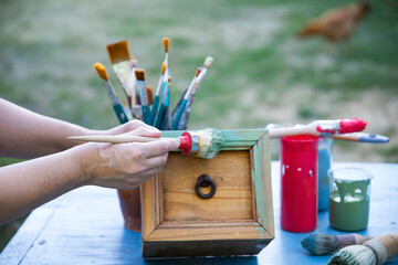 Painting a wooden furniture outdoors, an eco-friendly re-use business.