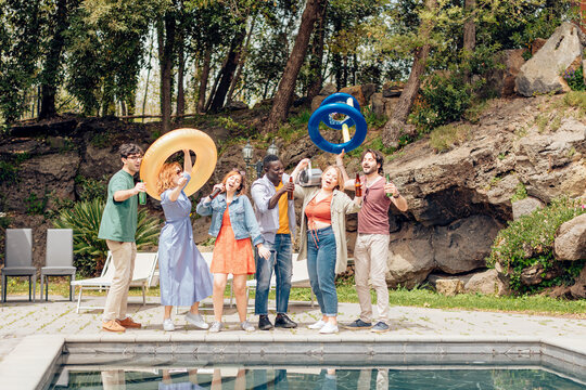 Friends singing and dancing by the pool at a summer party