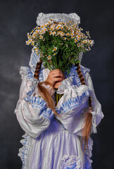 Smiling girl in vintage dress holding bouquet of daisies on dark background