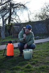 Young man engaged in household chores and small-scale rural farming, tending to his garden with...