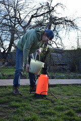 Young man engaged in household chores and small-scale rural farming, tending to his garden with...