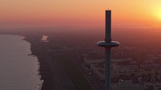 Drone orbit of Brighton&rsquo;s i360 Tower during golden hour, showcasing warm light, the cityscape in the background, and the modern coastal architecture.