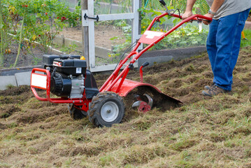 Man tilling a new garden with small motorized  plow machine. Expanding garden. rototiller. 