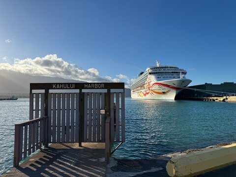 19 October 2024, USA, Hawaii, Maui, Kahului Harbor Bay - Norwegian Cruise Line NCL Sun docked in port on sunny day with hills and cityscape