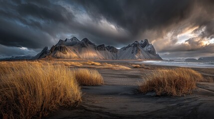 Dramatic mountain range meets a dark beach at sunset.