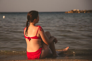 Pretty girl wearing red swimsuit resting on the beach,  summer vacations