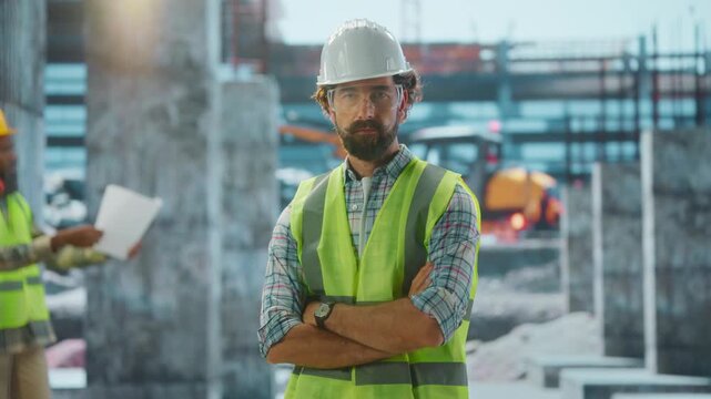 Construction engineer posing with crossed arms at building site