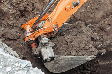 Close-up of an excavator bucket scooping dirt during foundation excavation for a new house after...