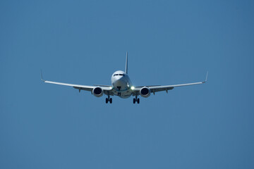 The plane approaching the airport. The plane is preparing to land. Airplane in the blue sky.