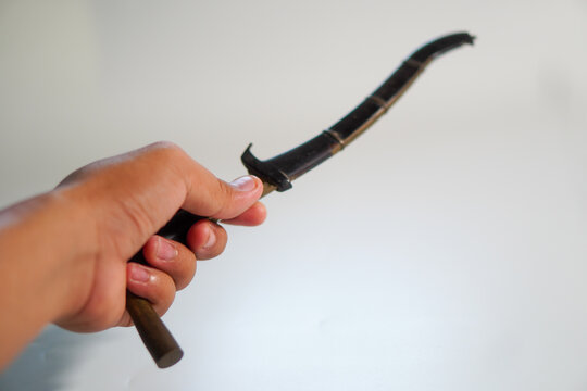 Hand holding Rencong or traditional Acehnese weapon with a unique shape and small size