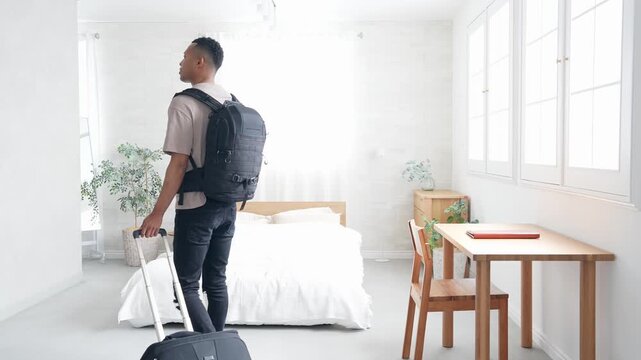 ホテルの部屋にスーツケースを持って立つ黒人男性旅行者