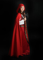 dramatic portrait of pretty young female brunette  model wearing a red hooded fairytale cloak and...