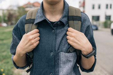 Unrecognizable student girl going to school holding backpack straps, morning routines