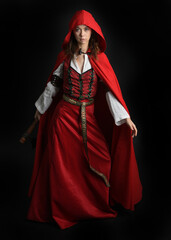 dramatic portrait of pretty young female brunette  model wearing a red hooded fairytale cloak and...