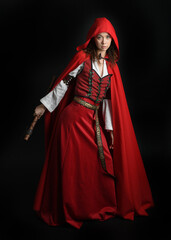 dramatic portrait of pretty young female brunette  model wearing a red hooded fairytale cloak and...