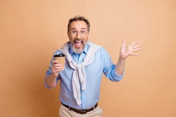 Confident mature gentleman holding a coffee cup while expressing joy and confidence on a beige...