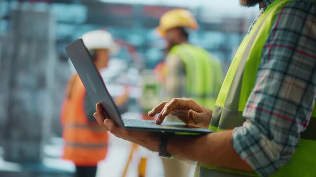 Construction engineer typing on laptop at building site