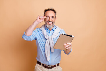 Professional mature man with tablet smiling confidently against beige background showcasing modern...