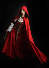 dramatic portrait of pretty young female brunette  model wearing a red hooded fairytale cloak and...