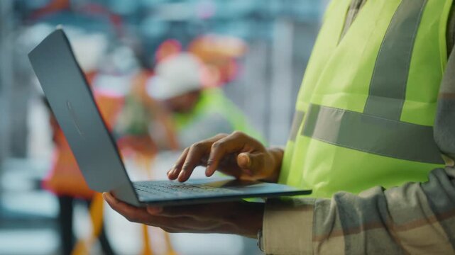 Engineer typing on laptop at construction site