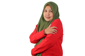 Modest Muslim woman hugging herself with calm expression and gentle smile
