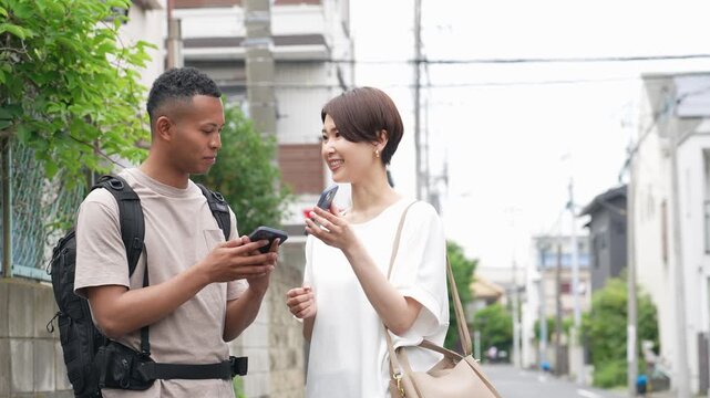 A Japanese woman conversing with a black man using a smartphone translation app