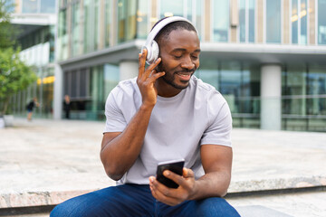 Music song concept. Good start day. Happy African American man listening modern hit on street in...
