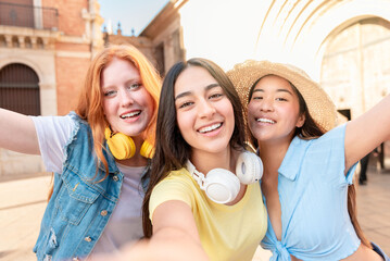 Happy three multiracial female friends taking selfie while enjoying summer holidays in the city