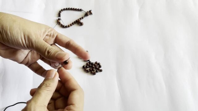An Asian woman is being creative in making handicrafts in the form of bracelets from wood grains.