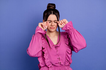 Young fashionable woman dressed in pink ruffled outfit poses in a studio against a blue background...