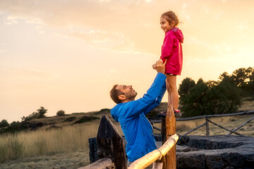 Father lifting his daughter up, symbolizing support, trust and future. A loving parent helping his...