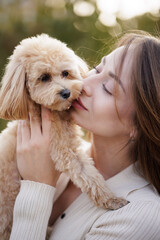 Woman kissing small dog showing love and affection outdoors
