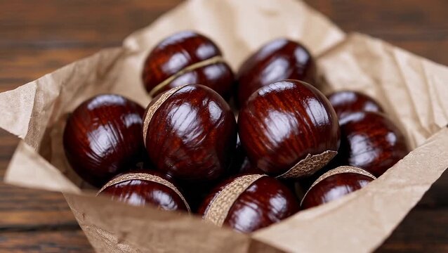 Fresh Shiny Brown Chestnuts in Rustic Paper Bag on Wooden Table