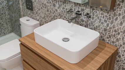 Fototapeta premium Focused image of a sleek white sink combined with wood cabinetry inside a luxury bathroom with modern patterned design