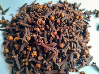 close up and texture of a pile of cloves on a white background