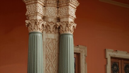 Decorative element of an Eclectic style building on a street corner displaying a partially green-painted, elaborately carved column.
