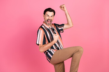 Enthusiastic man celebrating success while gesturing with excitement, posed on a vibrant pink...