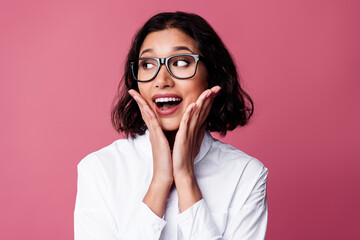 Fashionable young woman expressing surprise and delight against a pink backdrop