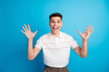 Happy young man with a cheerful expression showing open hands against a bright blue background