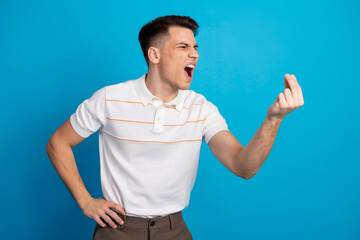 Young man making an expressive hand gesture against a blue background, showcasing casual style and...