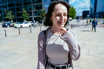Laughing young woman outdoors in city sunlight