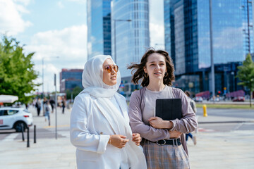 Two women standing near glass towers, one holding tablet