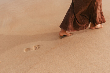 woman walking in sand leaving footprint