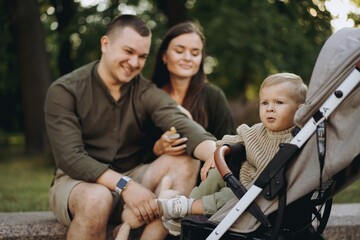young parents looking with love at their Baby son sitting in a stroller