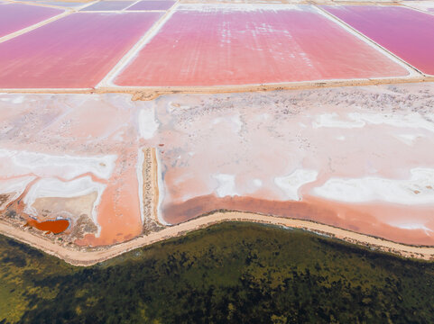 Aerial view of colourful salt evaporation ponds and levee banks at a coastal salt farm