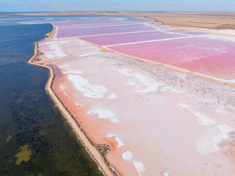 Aerial view of colourful salt evaporation ponds and levee banks at a coastal salt farm