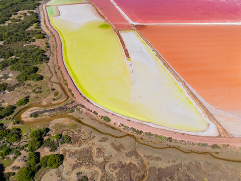 Aerial view of colourful salt evaporation ponds and levee banks at a coastal salt farm