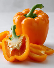 Bright orange bell pepper whole and sliced on white background
