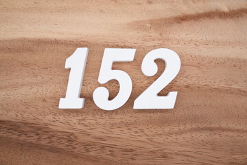 The numbers are made of white painted wood placed on a brown wooden floor.
